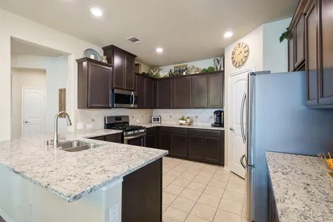 a kitchen with kitchen island granite countertop a sink refrigerator and cabinets