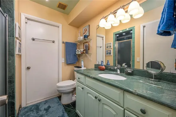 a bathroom with a granite countertop sink a toilet and a mirror
