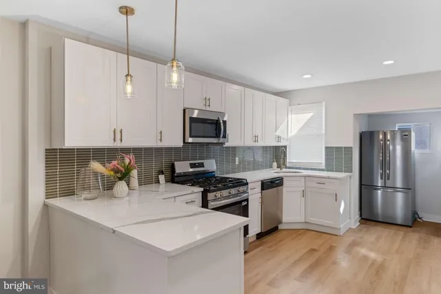 a kitchen with stainless steel appliances granite countertop a sink a stove a refrigerator and island with wooden floor