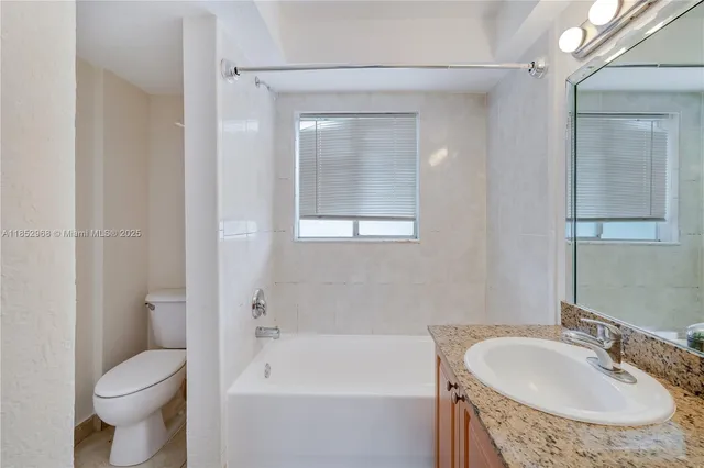 a bathroom with a granite countertop sink a mirror and a bathtub