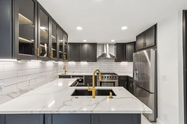 a kitchen with stainless steel appliances granite countertop a sink a stove and a refrigerator with wooden floor