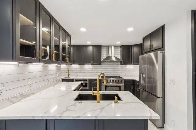 a kitchen with stainless steel appliances granite countertop a sink a stove and a refrigerator with wooden floor