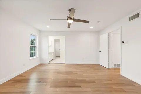 a view of empty room with wooden floor and ceiling fan