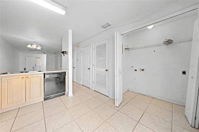 an empty room with chandelier fan and windows