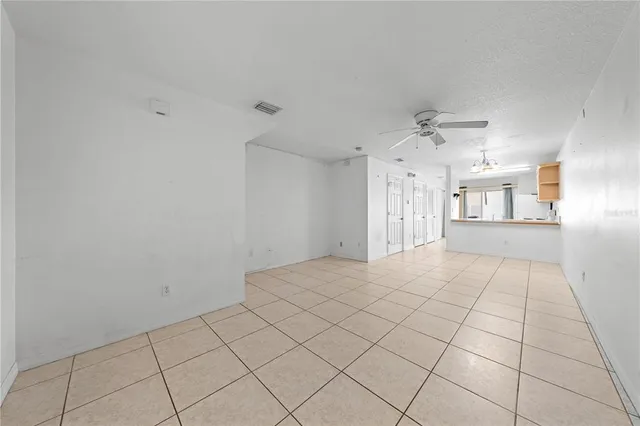 a view of an empty room and chandelier fan