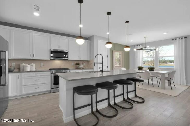 a kitchen with stainless steel appliances granite countertop a stove a sink a microwave a center island a table and chairs