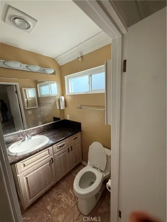 a bathroom with a granite countertop toilet sink and mirror