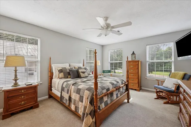 a bedroom with a bed a couch and a flat tv screen on the dresser