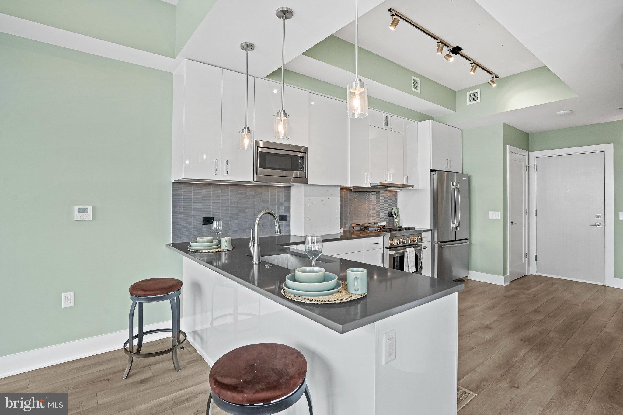 88 V Street Southwest, Unit 807 Washington, DC 20024 - Photo 15 of 57 a kitchen with stainless steel appliances granite countertop a sink a stove a refrigerator and island with wooden floor