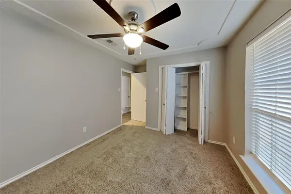 an empty room with closet and a ceiling fan