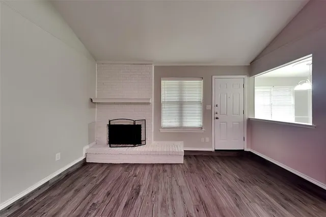 an empty room with wooden floor and fireplace