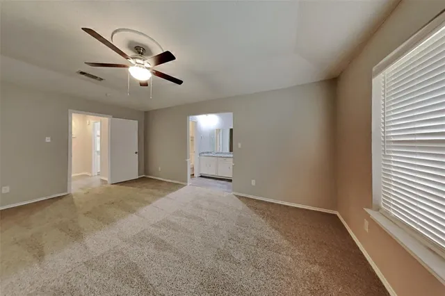 an empty room with windows and fan