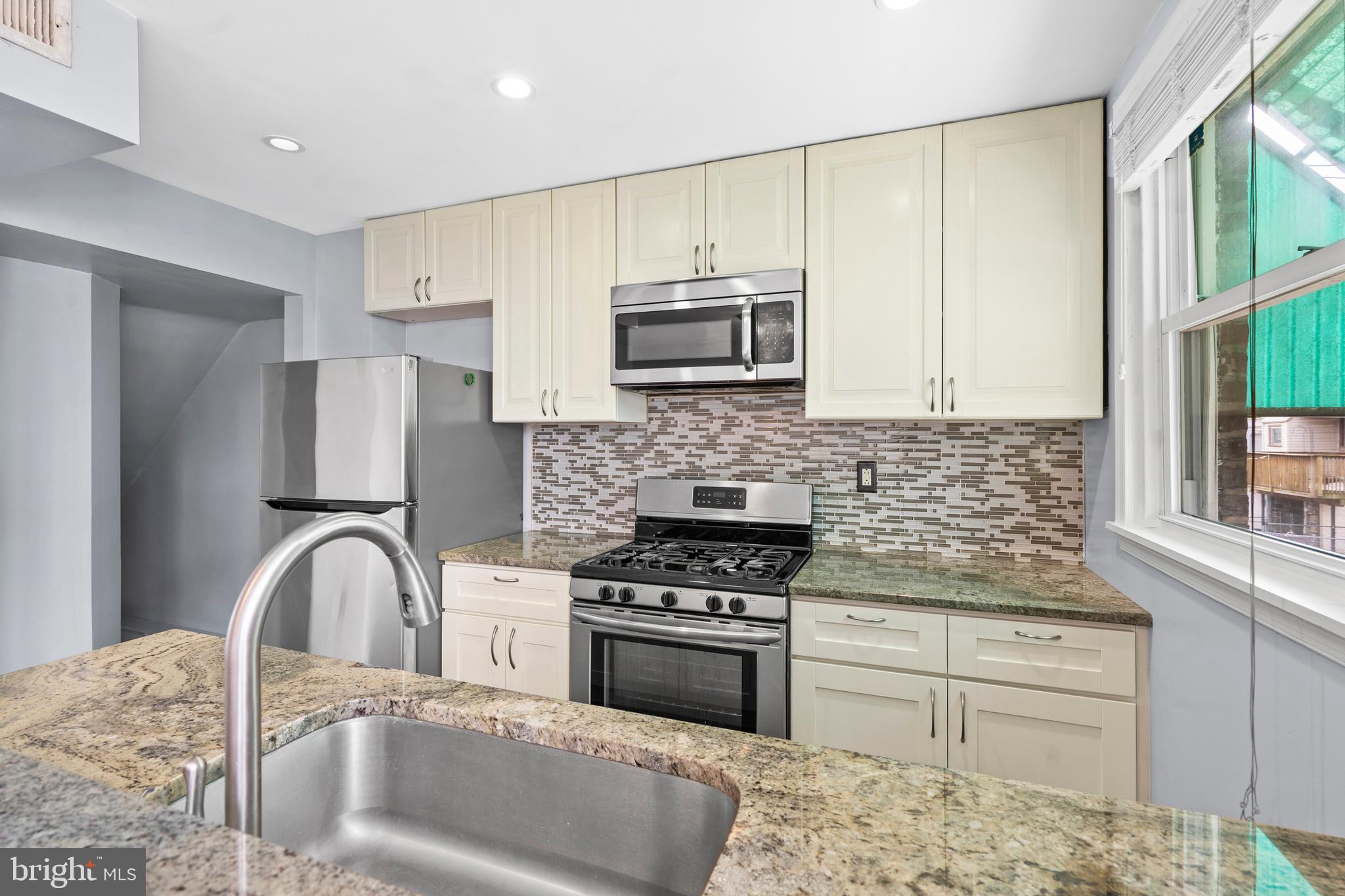 3522 Meridian Street Philadelphia, PA 19136 - Photo 6 of 18 a kitchen with granite countertop a stove a sink and a microwave