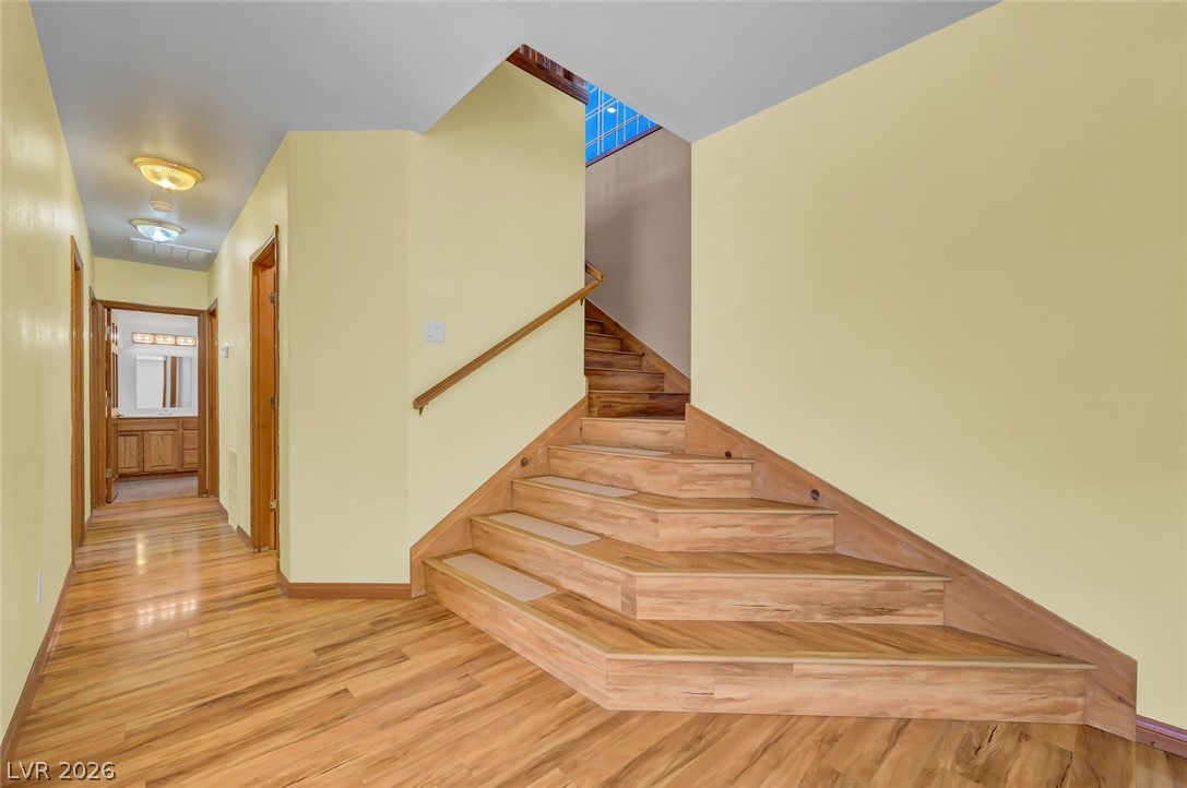 640 North Racetrack Road Henderson, NV 89015 - Photo 32 of 65 Hardwood flooring flows seamlessly from the hallway into a beautifully crafted wooden staircase.