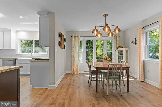 a dining room with wooden floor a chandelier a wooden table and chairs
