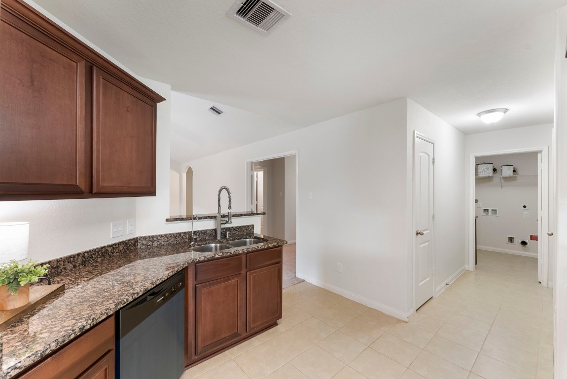 9159 Nina Road Conroe, TX 77304 - Photo 5 of 24 The kitchen features a brand-new black dishwasher, open sightlines to the living room, and convenient access to the utility room and garage—perfect for everyday functionality.