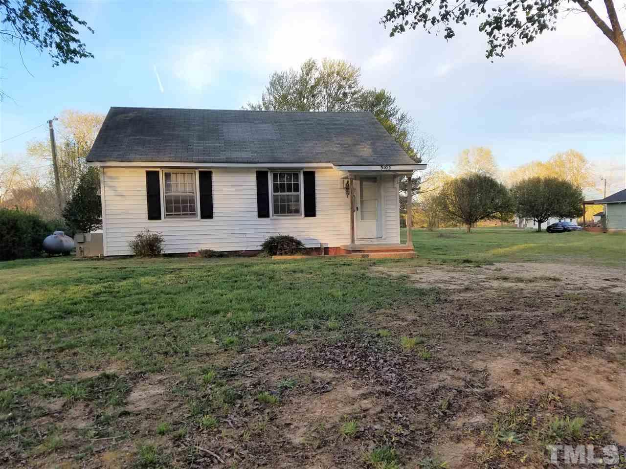 a front view of house with yard and trees all around