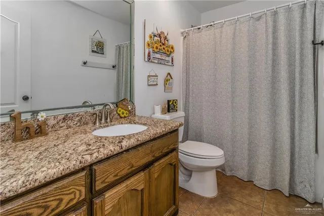 a bathroom with a granite countertop sink and a toilet