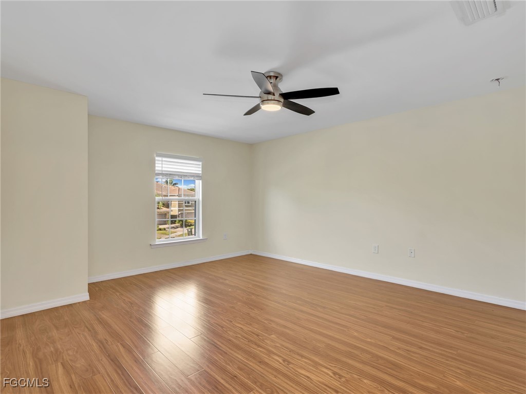 3886 Tilbor Circle Fort Myers, FL 33916 - Photo 23 of 30 an empty room with wooden floor ceiling fan and windows