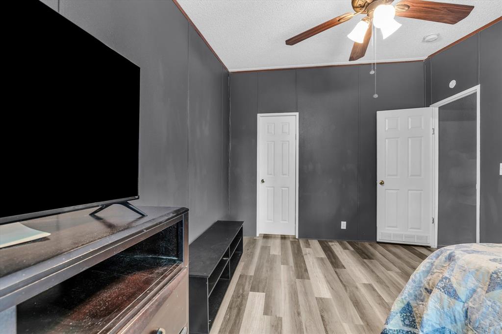 3615 Spring Valley Road Lorena, TX 76655 - Photo 10 of 33 Spacious room featuring wood-finish flooring, two white panel doors, a ceiling fan with light fixture, and dark gray walls