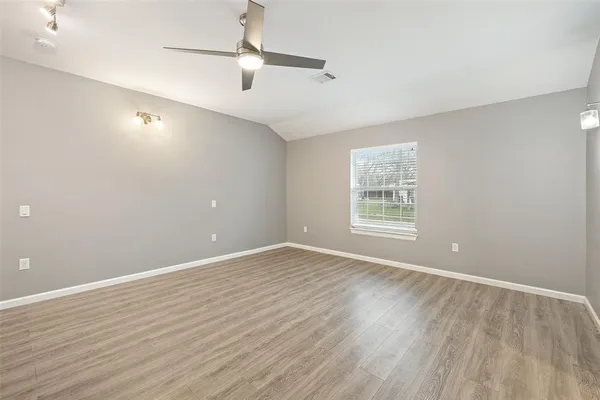 a view of an empty room with wooden floor and a window