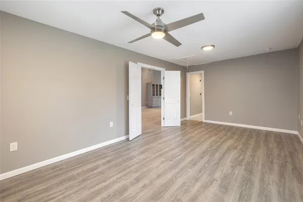 an empty room with wooden floor and ceiling fan