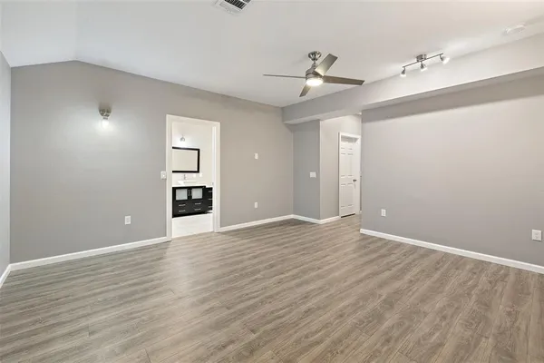 an empty room with wooden floor ceiling fan and windows