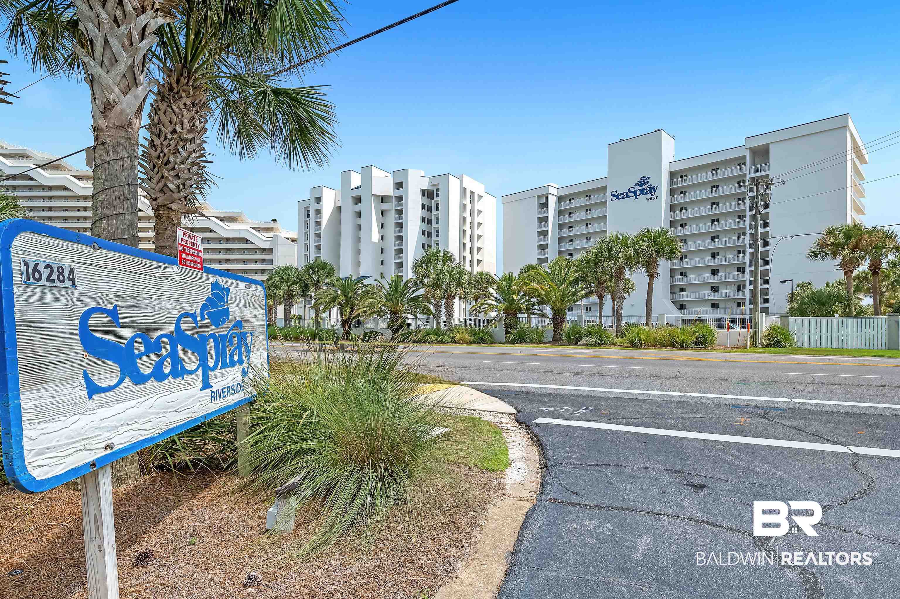 16287 Perdido Key Drive, Unit 105 Pensacola, FL 32507 - Photo 3 of 66 The "SeaSpray" sign marks the entrance to a multi-story building featuring multiple balconies and a white exterior