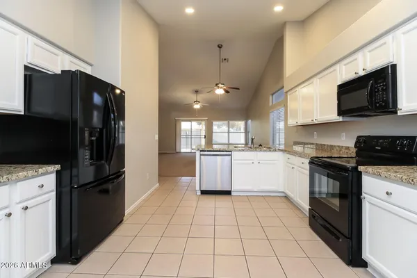 a kitchen with stainless steel appliances granite countertop a refrigerator a sink a stove top oven and cabinets