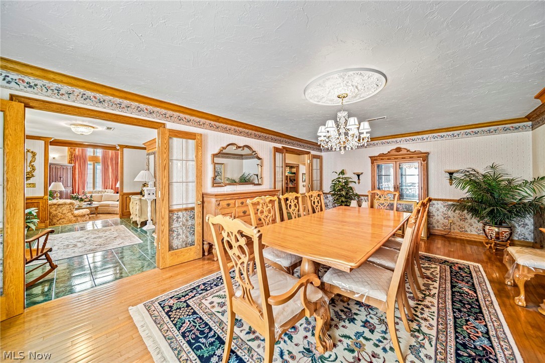 8801 Bunker Road Orwell, OH 44076 - Photo 16 of 50 Dining room with wood-type flooring, wallpapered walls, crown molding, a textured ceiling, and french doors