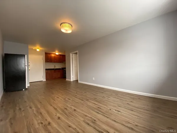 a view of an empty room with a window and wooden floor