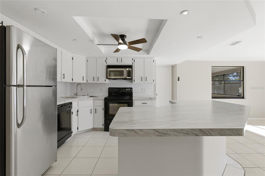 7230 San Moritz Drive Port Richey, FL 34668 - Photo 10 of 25 a kitchen with stainless steel appliances granite countertop a refrigerator a stove top oven a sink and dishwasher