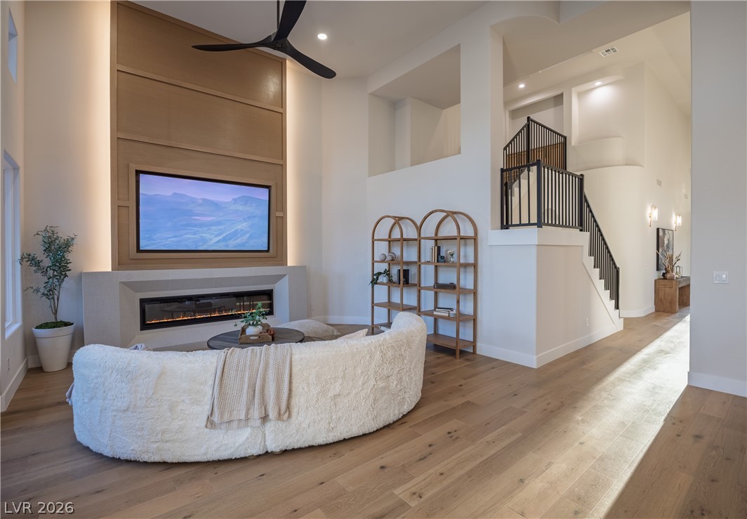 8800 Lusso Las Vegas, NV 89134 - Photo 26 of 85 Living area with hardwood / wood-style flooring, a high ceiling, a glass covered fireplace, a ceiling fan, and recessed lighting