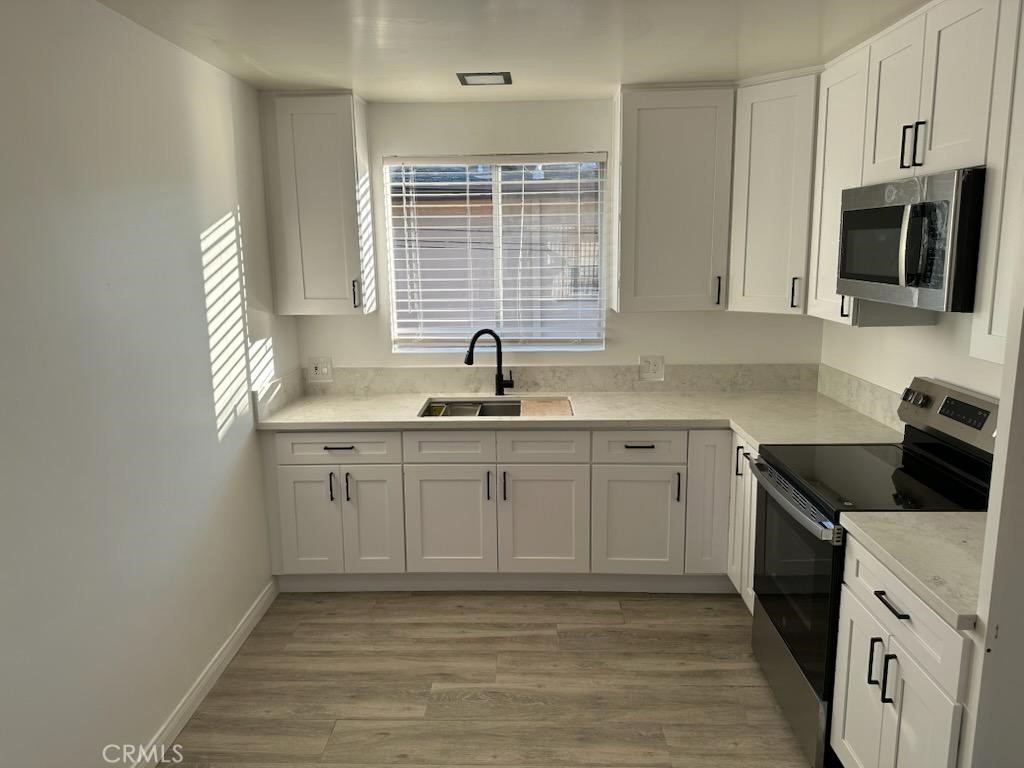 527 Cedar Avenue, Unit 2C Long Beach, CA 90802 - Photo 1 of 29 a kitchen with granite countertop a sink white cabinets and stainless steel appliances