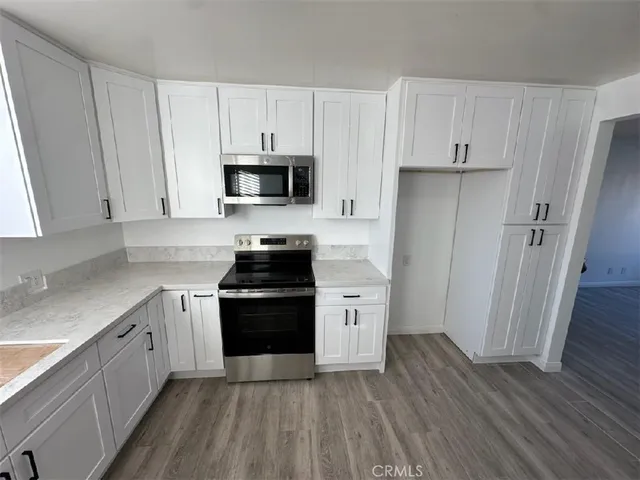 a kitchen with granite countertop white cabinets and stainless steel appliances