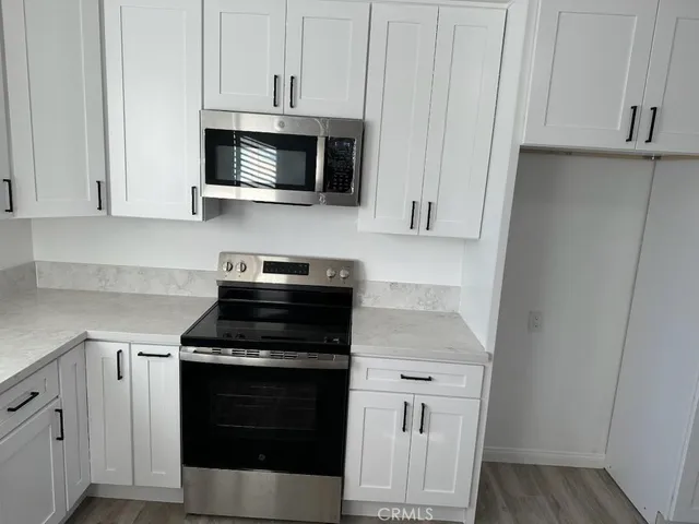 a kitchen with stainless steel appliances granite countertop white cabinets and a stove top oven