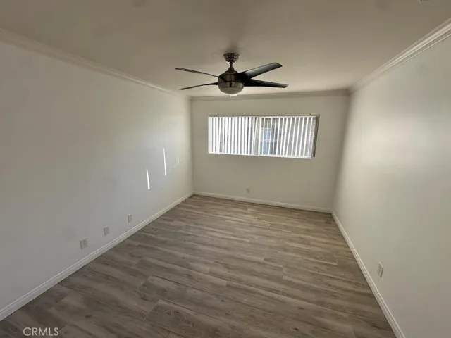 an empty room with wooden floor ceiling fan and windows