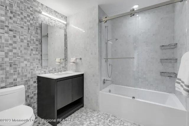 a bathroom with a bathtub shower sink vanity and toilet