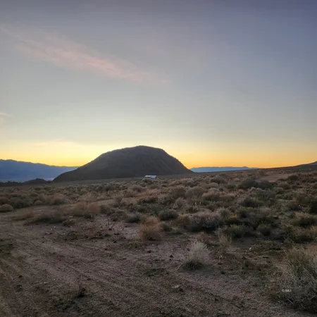 a view of a dry field with mountains in the background