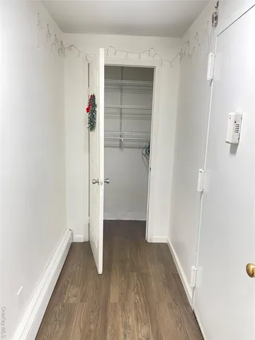 a view of a hallway with wooden floor and closet