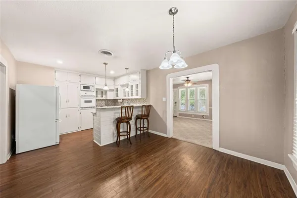 a kitchen with stainless steel appliances white cabinets and wooden floor