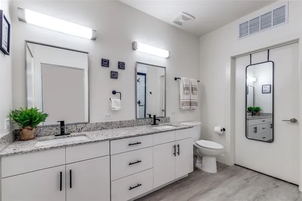 a spacious bathroom with double vanity a mirror and a shower