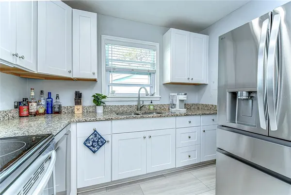 a kitchen with granite countertop white cabinets and stainless steel appliances