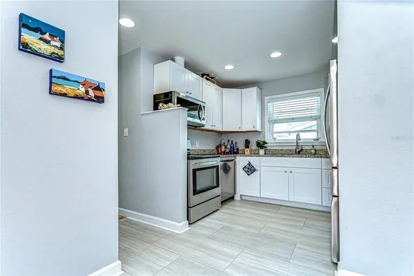 a kitchen with granite countertop white cabinets and white appliances