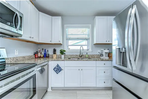 a kitchen with granite countertop white cabinets and stainless steel appliances