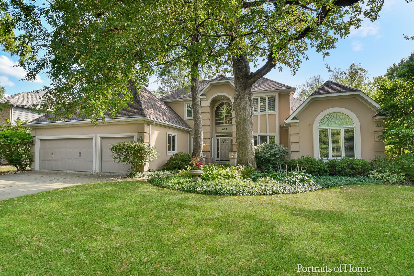a front view of a house with a garden and trees