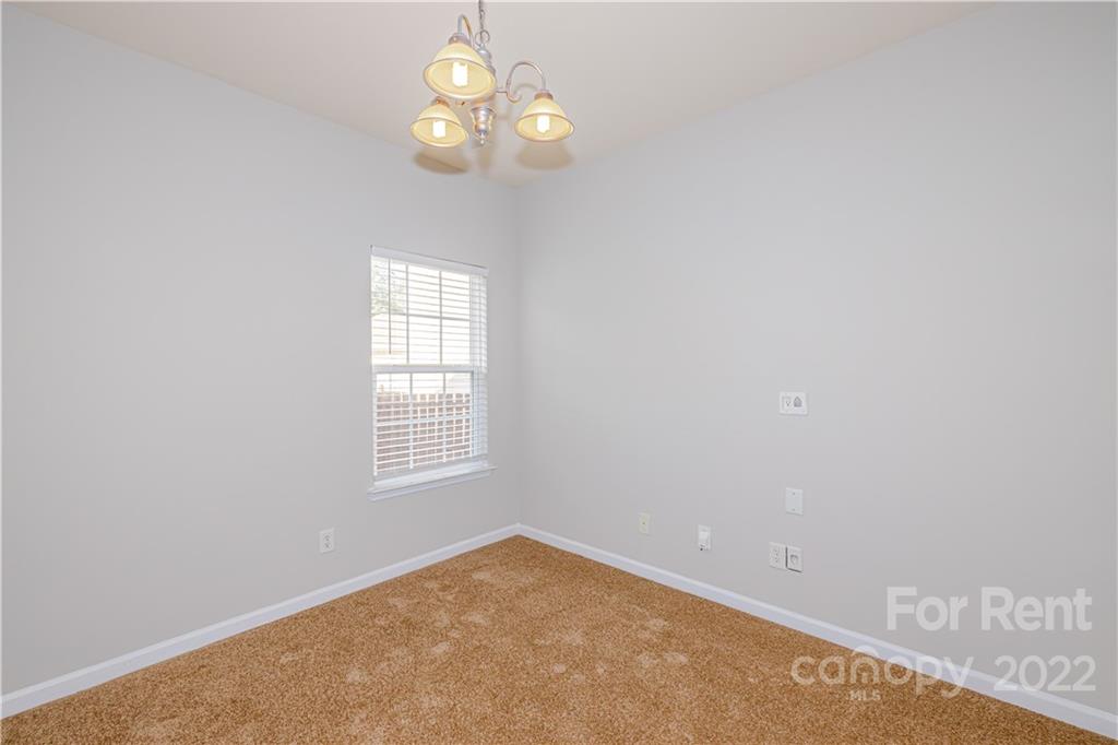 3329 Burnage Hall Road Harrisburg, NC 28075 - Photo 11 of 47 an empty room with a chandelier fan and windows