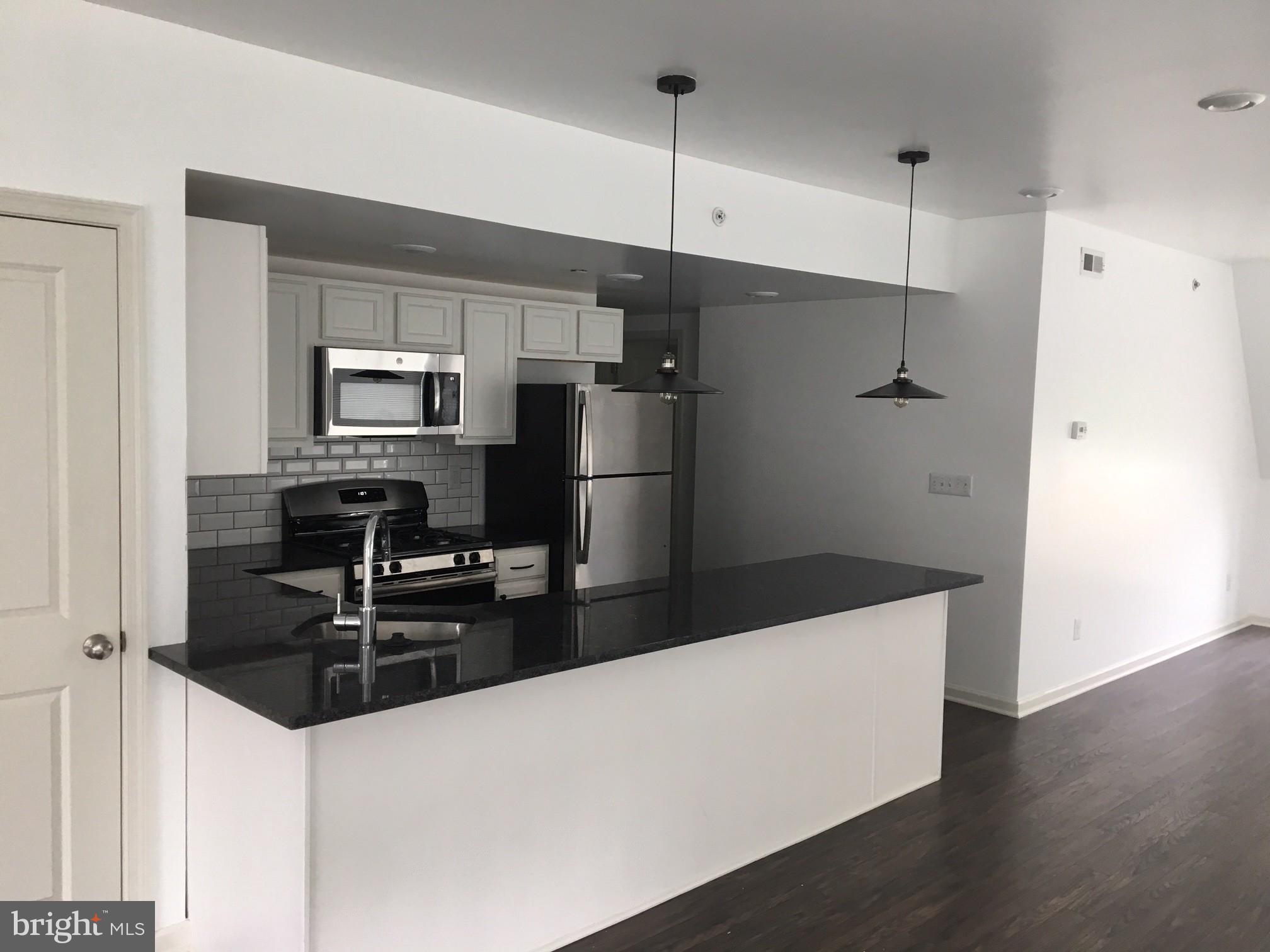 6619 Ridge Avenue, Unit 406 Philadelphia, PA 19128 - Photo 2 of 18 a kitchen with stainless steel appliances a refrigerator and a stove top oven