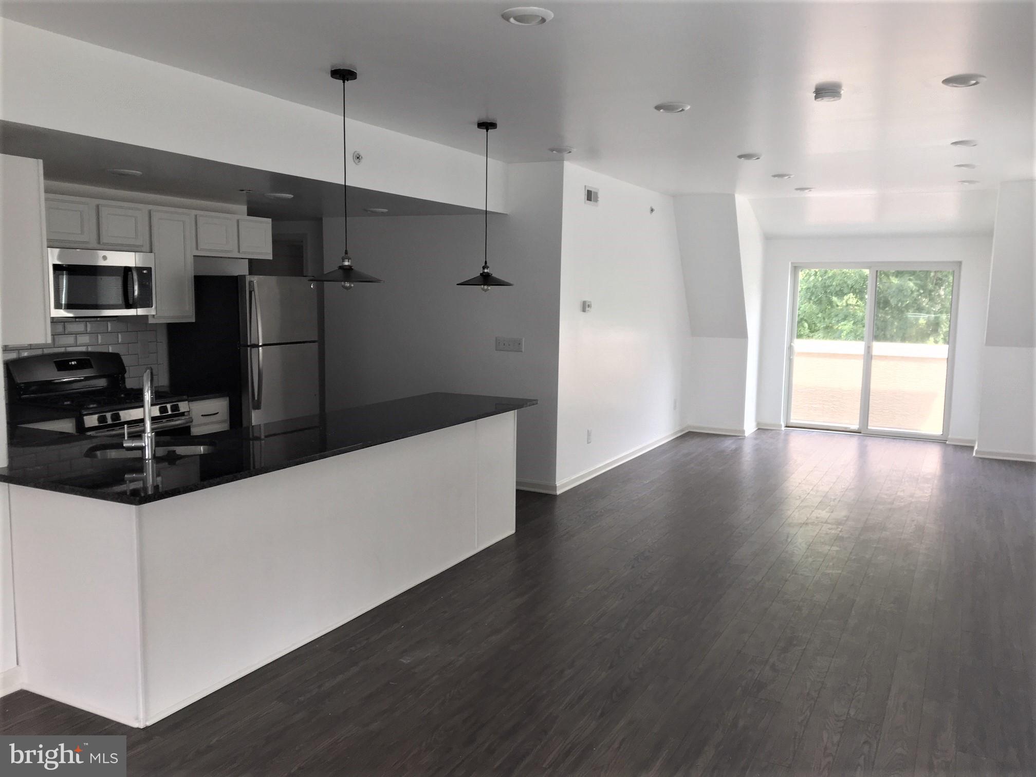 6619 Ridge Avenue, Unit 406 Philadelphia, PA 19128 - Photo 3 of 18 a kitchen with stainless steel appliances a refrigerator and wooden floor