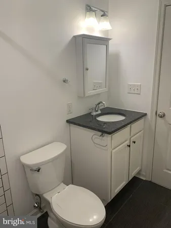 a bathroom with a granite countertop toilet sink and mirror